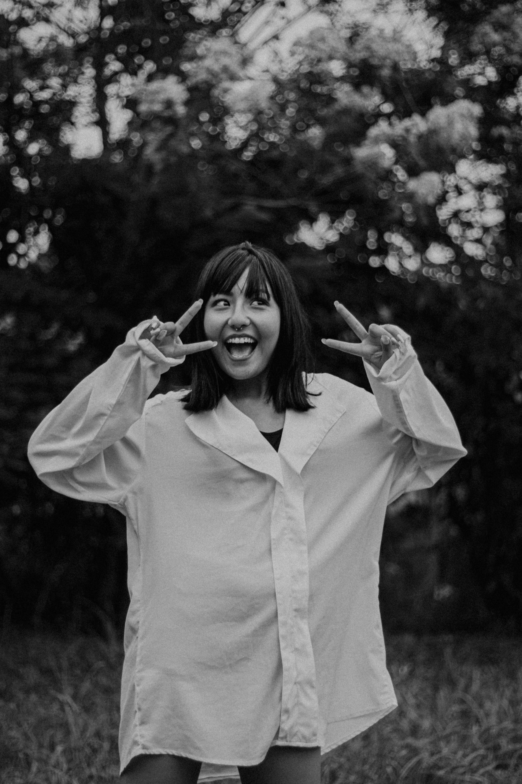 Happy woman in white shirt holding two fingers.