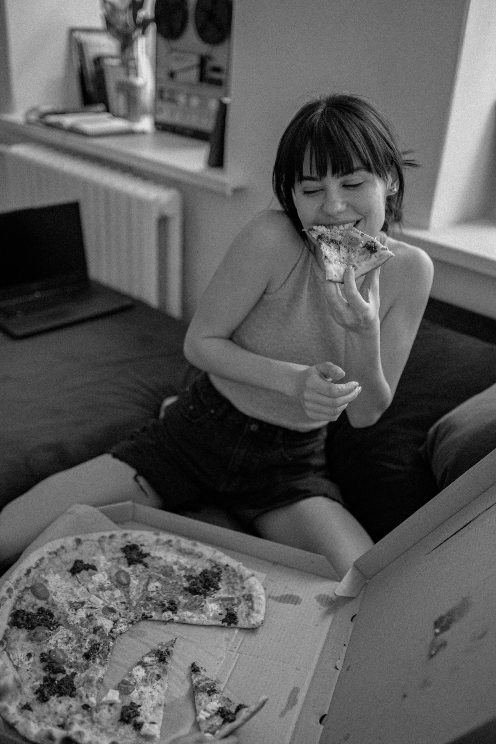 Happy woman eating pizza on her couch.