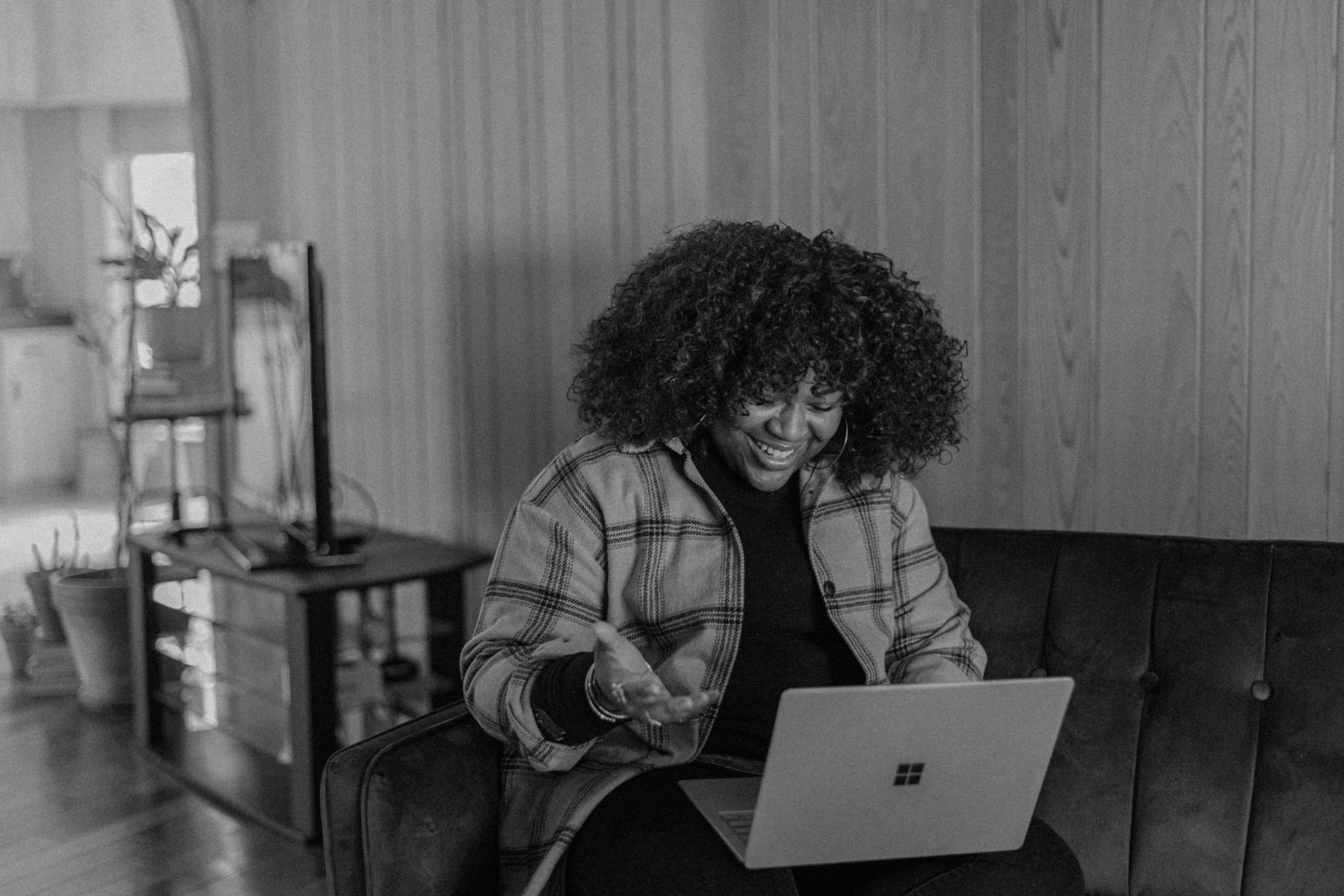 Happy woman sitting on her couch working on her laptop.